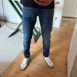 Blå jeans från Jack & Jones - Snygga blå jeans från Jack & Jones med klassisk femficksdesign och diskret tvättad look. Jeansen har normal passform och raka ben, perfekt för en avslappnad stil. Materialet är mjukt och stretchigt för extra komfort.