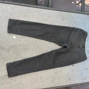 Svarta jeans - Svarta jeans med smal passform och klassisk femficksdesign. Jeansen har en enkel look utan synliga loggor och är tillverkade i ett mjukt denimtyg. Perfekta för dig som gillar en clean och stilren vibe.