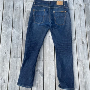 Mörkblå jeans från Nudie Jeans - Snygga mörkblå jeans från Nudie Jeans. Jeansen är i modellen ”Grim Tim” och har tvätten ”Dry true navy” och är i storleken W33 L30. Har andra jeans från nudie om det här är inte det du letar efter!