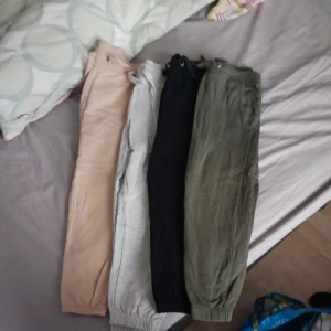 Fyra mjukisbyxor i olika färger - Säljer fyra par mjukisbyxor i beige, grått, svart och olivgrönt. Alla har resår och snörning i midjan samt muddar vid bensluten. Perfekta för chill dagar eller när du vill vara bekväm. Säljes tillsammans eller separat. För barn 