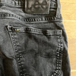  Lee jeans - Snygga svarta jeans från Lee som sitter i slim fit. Längden är L32. Femficksdesign och Lee-logga på bakfickan. Är tillverkade i stretchigt denimtyg för en bekväm känsla. Perfekta till sneakers eller boots.