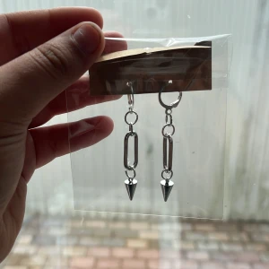 Silvriga örhängen med kedja och spike - Coola örhängen i silverfärg med kedjelänk och spetsig spike-detalj längst ner. Ger en edgy vibe och passar perfekt till streetstyle eller för att lyfta en enkel outfit. Säljs i par.