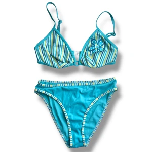 Turkos randig bikini med blomma - Så fin 2000s bikini! Har blomtryck på toppen! Överdelen är strl 75B och har bygel, underdelen är strl 36/38 (jag tycker den är lite stor på mig som brukar ha strl 36 på bikiniunderdelar). Använd köp nu <3