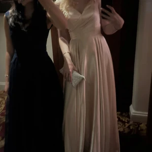 Rosa satin långklänning med snörning - Säljer en långklänning/balklänning i rosachampagnefärgat satinliknande material. Klänningen har omlottliv, v-ringning, smala axelband och snygg snörning i ryggen. Köpt på Ivory Fields. Orginalpris = 3300kr 