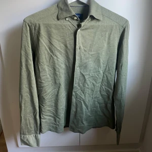 Grön skjorta från Eton - Säljer nu min gröna skjorta från Eton då den är för liten för mig. På bilderna är skjortan väldigt skrynklig, men stryker skälvklart upp den innan frakt. Skjortan är i ett väldigt bra skick och passar perfekt till dig som vill ha en stilren skjorta med en skön passform. 