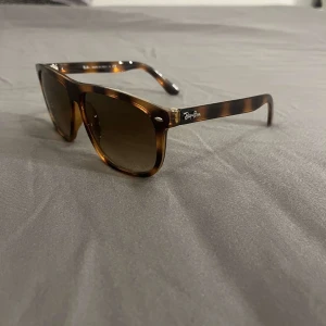 Ray-Ban Wayfarer brunmelerade solglasögon - Snygga Ray-Ban Wayfarer solglasögon med brunmelerad båge och bruna tonade glas. Klassisk fyrkantig form och diskret Ray-Ban-logo på skalmen. Tillverkade i Italien och perfekta för dig som vill ha en tidlös och cool look.