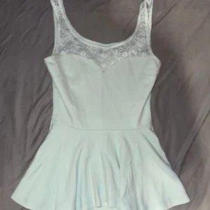 Blå spetstop från Gina Tricot - Supersöt ljus blå topp från Gina Tricot med spets upptill och ärmlös design. Toppen har en figurnära passform upptill. Perfekt för dig som gillar romantiska detaljer och vill ha en feminin look.