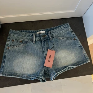 Blå jeansshorts från YESCCI - Snygga lowwaist jeansshorts från YESCCI med klassisk femficksdesign och bälteshällor. Shortsen har normal passform och är tillverkade i mjukt denimtyg. Perfekta för varma dagar och enkla att matcha med allt.