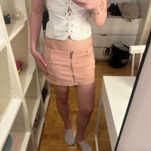 Ljusrosa kortkjol med dragkedja - Assnygg rosa jeanskjol i bra skick! Liten defekt syns på bild 4 men går enkelt att sy igen och annars inget som märks! 