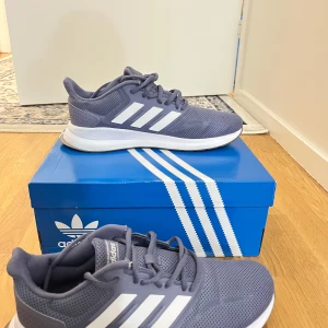 Grå sneakers från Adidas med mesh - Säljer ett par Adidas sportskor i fint skick. De är använda men fortfarande hyfsat nya och väldigt sköna att ha på sig. Klassisk design med vita ränder. Perfekta för både träning och vardag. Säljer dem bara för att de tyvärr är för stora för mig. Passar väldigt bra för att till exempel gå ut och springa eller bara ha på sig de till vardags 🏃‍♀️‍➡️ OBS! Köparen står för frakt!