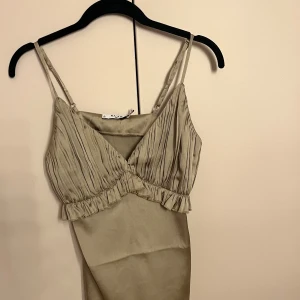 Beige satinlinne från NAKD - Beige/champangefärgat satinlinne med volang från NAKD i storlek xs, aldrig använt.🤎