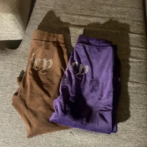 Juicy Couture mjukisbyxor brun & lila S - Två par ikoniska Juicy Couture mjukisbyxor i storlek S, ett par i chokladbrunt och ett par i lila. Båda har glittrande strasstexten 'juicy' på höften och är gjorda i mjuk, skön velour. Perfekta för en chill och trendig look. Jag tar 150 för båda! 