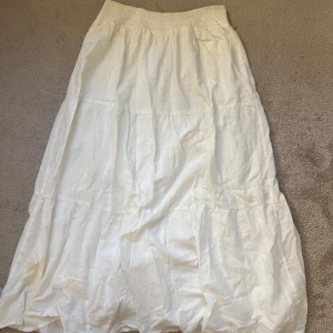 Vit långkjol från MNG i bomull - Säljer en luftig och flowy vit långkjol från MNG. Kjolen har resår i midjan och är sydd i flera volanger för en extra snygg och avslappnad look. Perfekt för varma dagar när du vill ha något bekvämt och stilrent. Jättefin.