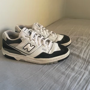 New Balance 550 svartvita sneakers - Snygga New Balance 550 sneakers i svart och vitt med klassisk retrodesign. Skorna har tydliga loggor på sidan och tungan, snörning och en robust platt sula. Ovandelen är i skinn och mocka, vilket ger en schysst kontrast mellan materialen. OBS Nike innersula. Ny pris 1000 kr. Hör av er om ni har frågor! 
