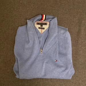 Ljusblå quarterzip Tommy Hilfiger xs -  ljusblå quarterzip från Tommy Hilfiger storlek xs. Har aldrig använt den, fick som present men den var för liten. Säljs för 200 kr Finns i Sthlm