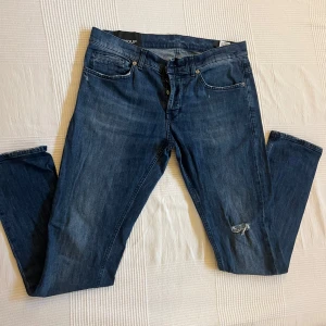  Dondup George Skinny Fit Jeans mörkblå storlek 34  - Snygga mörkblå jeans från Dondup med klassisk femficksdesign och slitna detaljer på benet och bakfickan. Storlek 34 