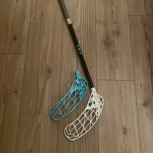 Ultralight Innebandyklubba - Snygg och lätt innebandyklubba med två blad (ett vitt och ett blått). Perfekt för dig som vill ta ditt spel till nästa nivå, oavsett om du är nybörjare eller proffs. Greppvänligt handtag och modern design gör den till ett självklart val för unga spelare. OBS! Jag kan sänka priset till 1000 men då får man bara med ett blad.