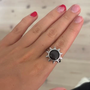 Silversolring med svart sten SbyS - Cool ring i äkta silver (925) från Sophie by Sophie med en stor, rund svart sten i mitten och taggiga detaljer runt om som ger en sol-liknande vibe. I storlek 19 mm