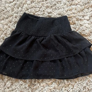 Svart glittrig volangkjol Gina Tricot - Supersöt svart volang  kortkjol från Gina Tricot med glitter paljetter. Den sitter jättebra. 