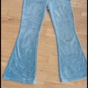Blå velourbyxor från Lindex Kids - Snygga blå velourbyxor från Lindex Kids i storlek 140. Byxorna har utsvängda ben och är gjorda i mjuk polyester som känns riktigt skön mot huden. Perfekta för dig som gillar retrovibbar och vill ha något bekvämt men ändå trendigt.
