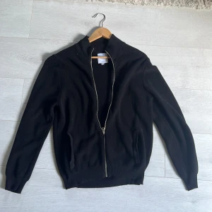 Svart stickad kofta från Erla - Svart stickad kofta från Erla of Sweden med hel dragkedja framtill. Använd men fortfarande bra skick!