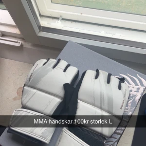 Vita MMA handskar från Decathlon L - Säljer ett par vita MMA handskar från Decathlon i storlek L. Handskarna har öppna fingrar och bred kardborreknäppning runt handleden. Snygg sportig design med svarta detaljer och gråa linjer. Perfekta för kampsportsträning eller sparring.