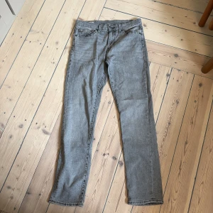 Grå Levis 511 jeans straight fit - Snygga grå Levis 511 jeans med klassisk femficksdesign och raka ben. Jeansen har en normal passform och är tillverkade i mjukt denimtyg. Perfekta för dig som gillar en stilren look med lite edge.