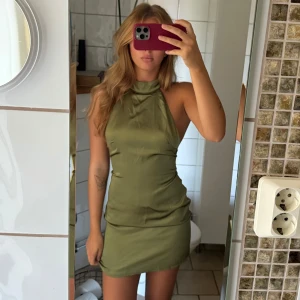 Olivgrön halterneck miniklänning - Snygg olivgrön miniklänning med halterneck och öppen rygg. Klänningen har en tight passform och  materialet är slätt och har en lätt glansig finish✨⭐️