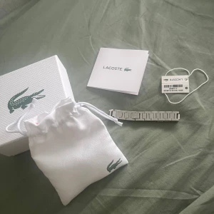 Silverfärgat armband från Lacoste - Stilrent armband från Lacoste i silverfärgad metall med länkdesign och graverad krokodil på en av länkarna. Kommer med original ask, tygpåse och tag. Perfekt accessoar för dig som gillar en clean och sportig look. Skriv i dm för mer info!