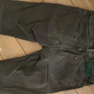 Grå/gröna jeans från Jacob Cohen, stl 32 - Säljer ett par grå jeans från Jacob Cohen i storlek 32. Byxorna har klassisk femficksdesign, raka ben och snygga detaljer vid fickorna. Tillverkade i bomull med en skön passform och diskret logga på myntfickan. Perfekta för en stilren och avslappnad look.