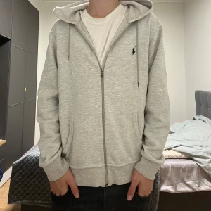 Grå hoodie från Ralph Lauren - Snygg ljusgrå hoodie från Ralph Lauren med dragkedja. Jätte najs passform och känsla. Hör av dig om du har nån fråga
