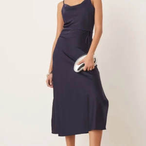 Marinblå långklänning från YAS - Säljer en stilren marinblå långklänning från YAS med smala axelband och lätt draperad halsringning. Klänningen är gjord i ett mjukt, glansigt material som ger en lyxig känsla. Helt ny med prislappar kvar! 
