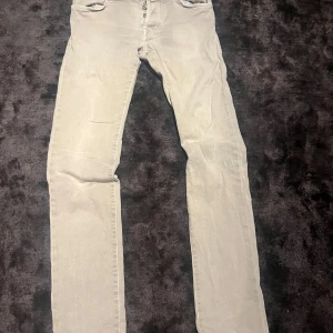 Beige jeans från Jacob Cohën, stl 32 - Snygga beige jeans från Jacob Cohën i klassisk rak modell. Byxorna har fem fickor, knappgylf och diskret logga på bakfickan. Perfekta för dig som gillar stilrena och neutrala färger. Materialet känns mjukt och följsamt.