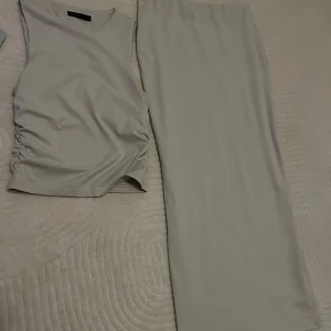 Beige långkjol och topp  - Säljer en stilren beige långkjol med toppen. Kjolen och toppen  är gjord i ett mjukt och stretchigt syntetmaterial som känns skönt mot huden. Perfekt för dig som gillar minimalistisk och clean look. 