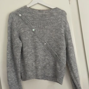 Grå stickad tröja med knappar  - Supermysig grå stickad tröja från Design by Si med unika knappar 🌺🌺knappt använd och jättesnygg design. Strlk M/L men sitter mer som en S
