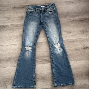 Blå bootcut jeans med slitningar - Snygga blå bootcut jeans från Gina Tricot med slitningar på knäna och coola röda broderier på bakfickorna. Jeansen har kontrastsömmar i gult och rött, klassisk femficksdesign och en lätt tvättad look. Perfekta för dig som gillar en avslappnad och trendig stil. använd en gång men de e ett litet hål vid gylfen💓