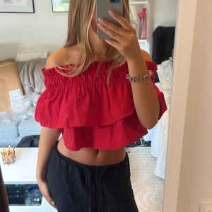Röd offshoulder croppad blus - Säljer en helt ny oanvänd röd offshoulder blus med volanger och smockad överdel. Toppen är croppad och har en luftig passform. Klicka gärna på ”köp nu”💕