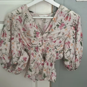 Blommig blus med puffärm, M - Supersöt blommig blus med v-ringning och bred resår i midjan. Puffiga trekvartsärmar. Använd få tal gånger, som ny. 💕
