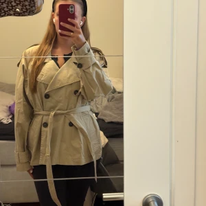 Kort trechcoat - Skitsnygg kort trenchcoat men som tyvärr är lite stor på mig. Helt ny med prislapp, går att ta av snöret kring magen om man vill de. Slutsåld på ginas hemsida, perfekt höstjacka, hör av dig vid frågor☺️