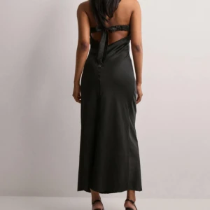 Svart bandeauklänning - Svart långklänning från ONLY. Axelbandslös modell med knytning och öppen rygg. Perfekt till finare tillfällen. Aldrig använd och prislapp kvar. Nypris 499.