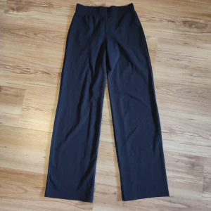 Svarta vida byxor från Gina Tricot XS - Svarta byxor från Gina Tricot i storlek XS. De har en hög midja och vida, raka ben. Tillverkade i stretchigt material med 96% polyester och 4% elastan för en bekväm passform. Perfekta för en clean och stilren look. De går att göra ännu vidare då jag har sytt in dem lite i benen (se blod 4)