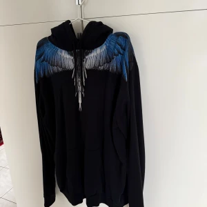 Svart hoodie med blå vingar från Marcelo Burlon - Säljer en svart hoodie från Marcelo Burlon, stor i storleken