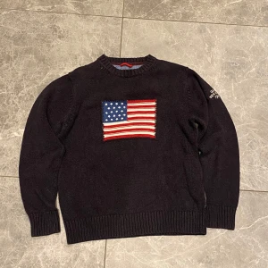 Svart stickad tröja från GANT med USA-flagga - Säljer en svart stickad tröja från GANT i storlek M. Tröjan har en broderad amerikansk flagga på bröstet och vit text på ena ärmen. Rund hals och ribbade muddar vid ärmslut och nederkant. Perfekt för dig som gillar klassisk stil. Hör gärna av dig om du är intresserad eller har några frågor!!