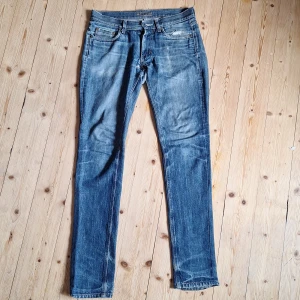 Blå Acne Jeans MIC Rigid 31/34 - Säljer ett par klassiska blå jeans från Acne Jeans, modell MIC Rigid. Jeansen har raka ben, normal/slim passform och är tillverkade i 100% bomull. Snyggt slitna (raw denim). Diverse lagningar (se bild) vilket bara bidrar till jeansens look. Kontakta mig vid frågor!