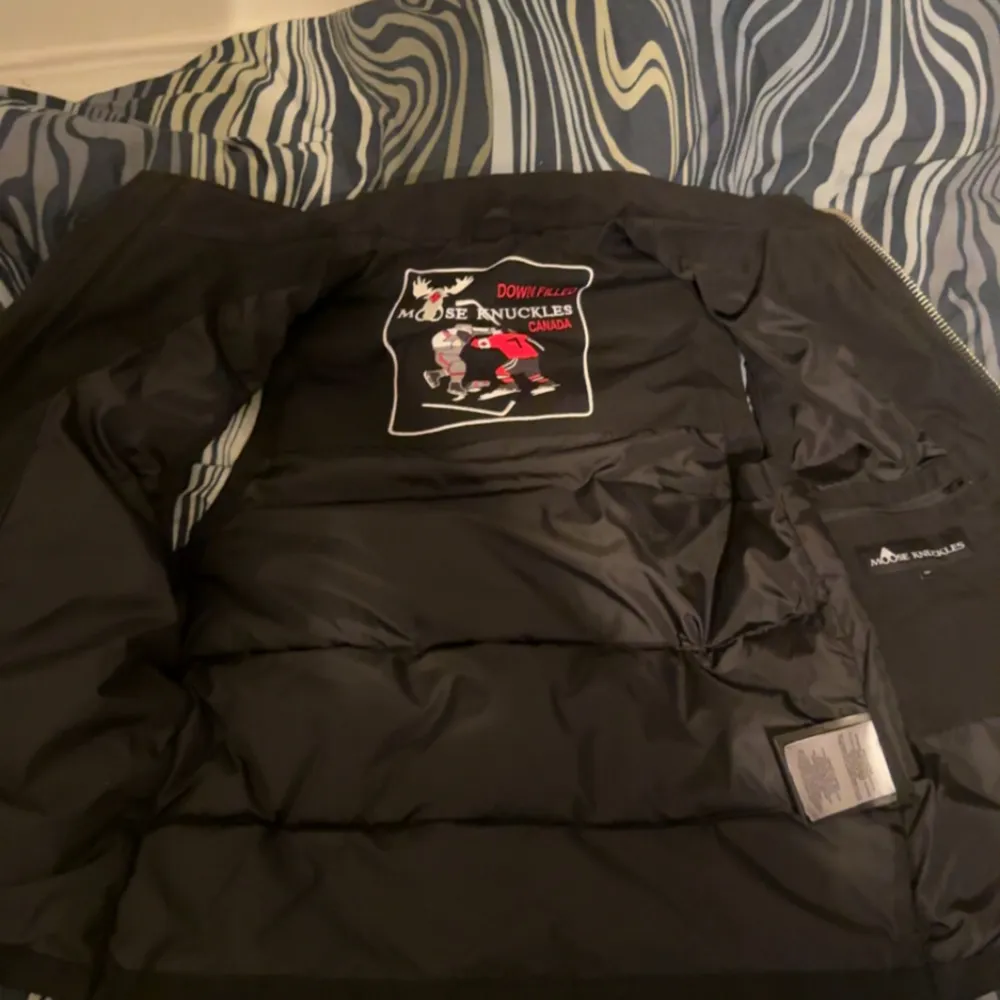 Tjenixen! Säljer nu min snygga svarta dunväst som inte går att få tag på igen ifrån Moose Knuckles med dragkedja och logotypdetaljer som passar perfekt för kyligare dagar med sin quiltade design. Västen har en stilren look och är lätt att matcha med olika outfits! Anledningen till varför jag säljer den är för att den inte riktigt matchar min garderob längre och den är köpt på johnells förra året i juli men väldigt sparsamt använd.. Takit.