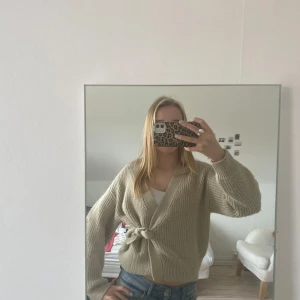 Beige omlott stickad kofta  - Säljer en mysig beige stickad kofta med knyt framtill. Koftan har långa ärmar och en avslappnad passform, perfekt för kyligare dagar. En stilren och bekväm tröja som passar till det mesta.