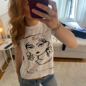 Vit t-shirt med konstnärligt tryck - Säljer en vit t-shirt från Zara med ett coolt konstnärligt tryck av ett ansikte. T-shirten har korta ärmar och en normal passform. Perfekt för att ge din outfit en unik touch!