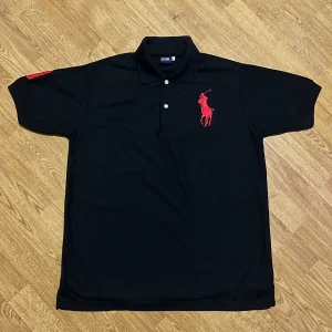 Svart pikétröja  - Riktigt snygg svart pikétröja i storlek L. Helt ny. Tyvärr inte äkta men riktigt fet ändå.