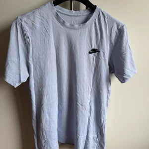 Ljusblå t-shirt från Nike - Säljer en stilren ljusblå t-shirt från Nike med korta ärmar och en liten broderad logga på bröstet. Ursäkta att den är lite skrynklig men det beror endast på att den legat i garderoben🙏Storlek: S