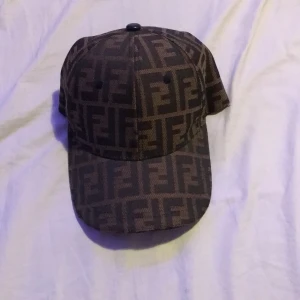 Brun keps från Fendi - Tjena, säljer en väldigt snygg brun keps från Fendi . Kepsen har en klassisk design med justerbar rem baktill för bästa passform. Perfekt till en solig sommardag. Använd endast ett fåtal gånger och i väldigt bra skick, tveka inte att skriva om några funderingar 